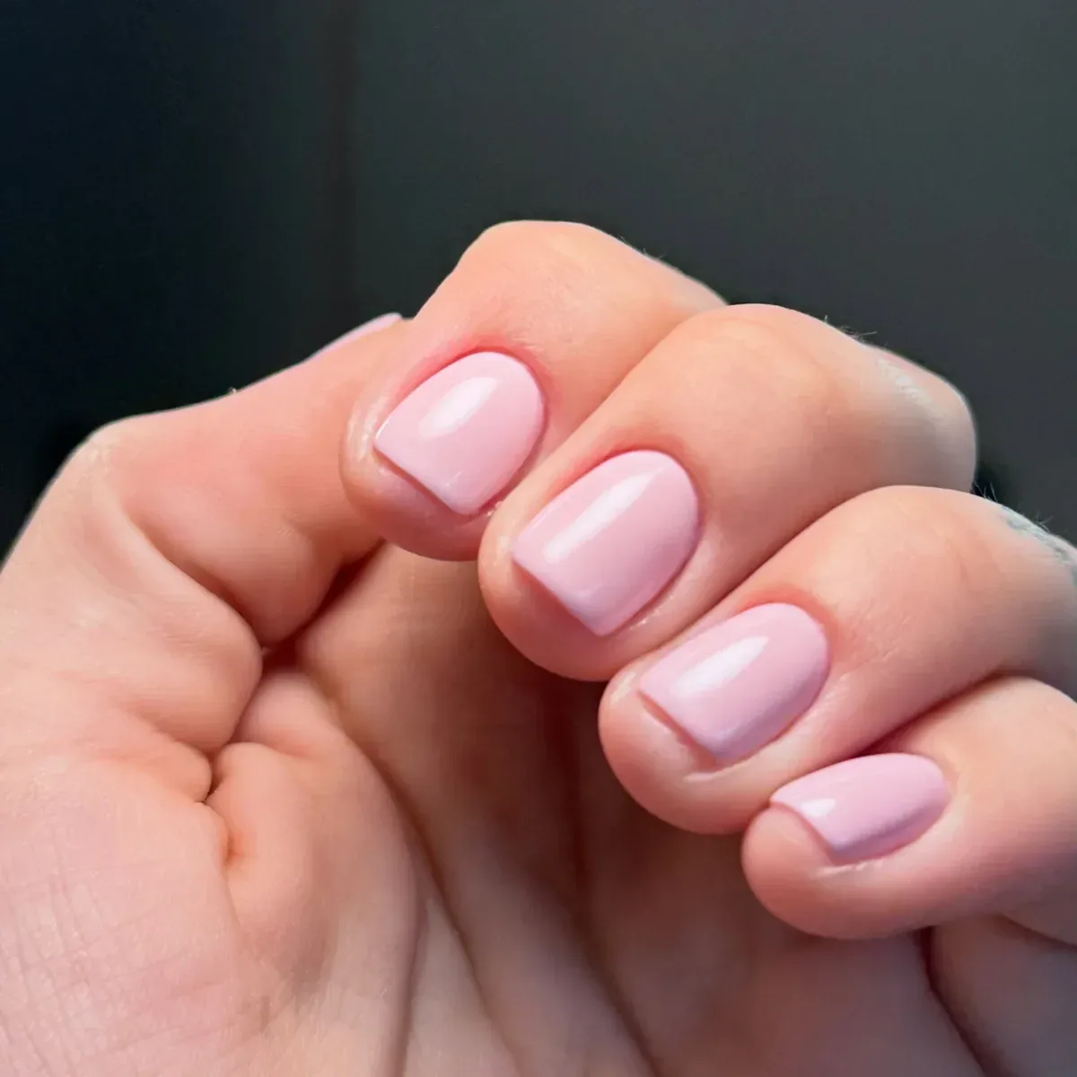 Unhas curtas e arredondadas em rosa leitoso, com brilho uniforme e cutículas limpas